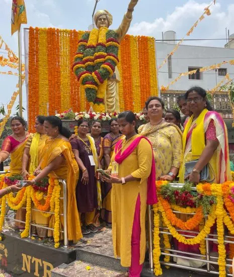 Party women in TDP yellow gathered around a garlanded statue of N. T. Rama Rao before a rally.